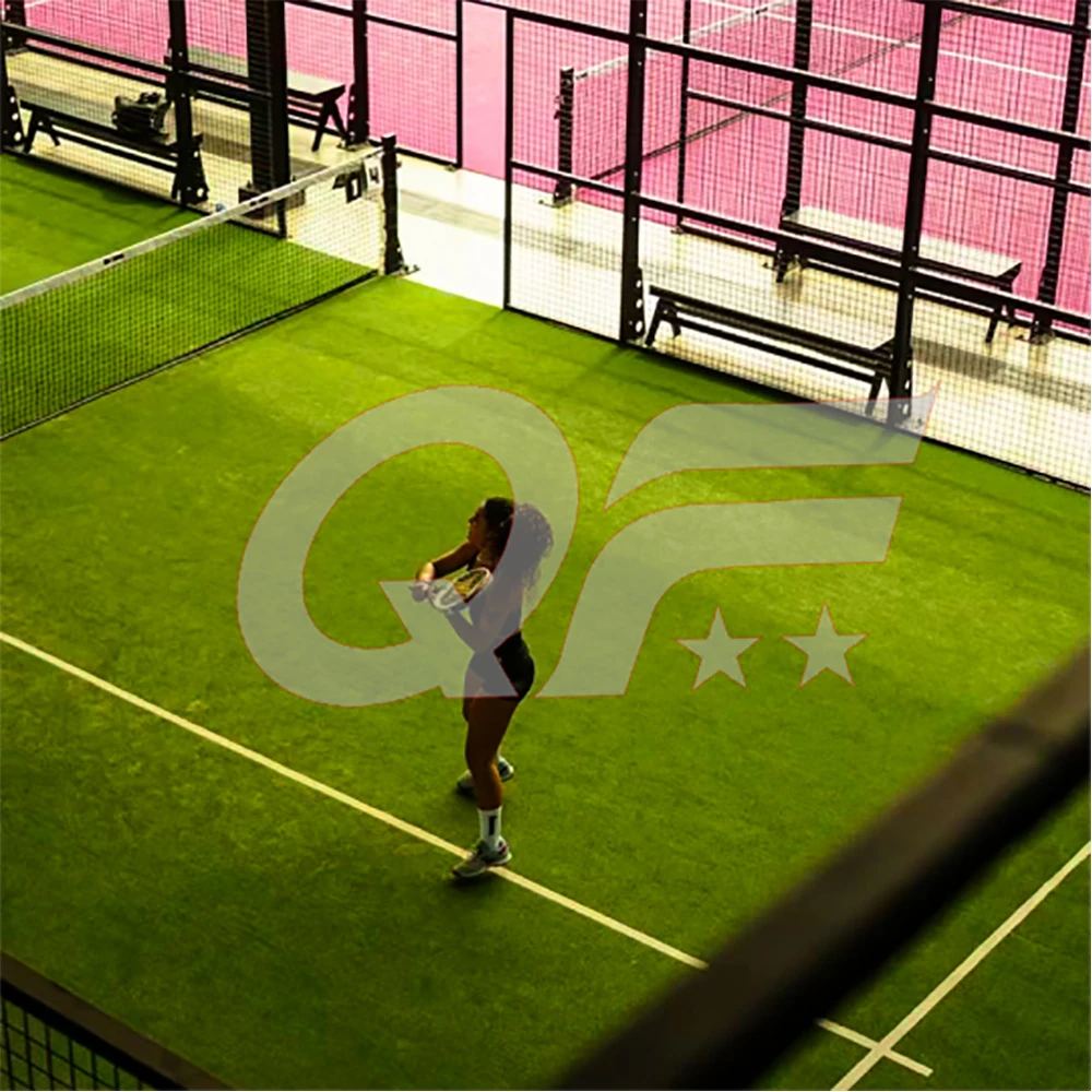 padel court with player practicing on artificial turf surrounded by glass walls and fencing